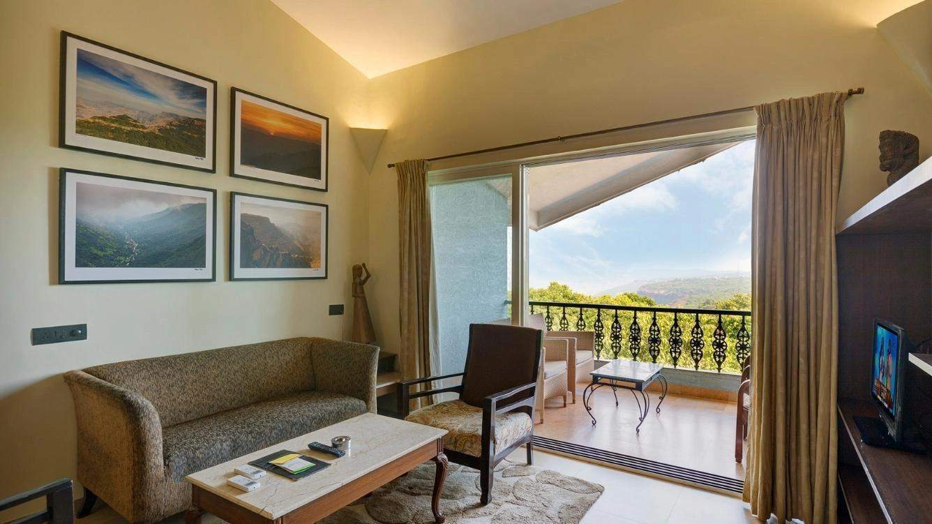 Stylish bedroom featuring wooden furniture, natural lighting, and greenery views from the window at Ramsukh Resort.